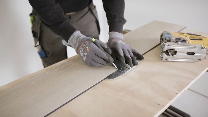 man using tools to saw a vinyl floor